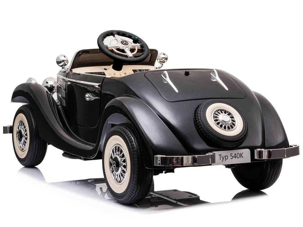 Schwarzes Retro-Kinderauto im Stil eines Oldtimers "Typ 540K", hinten links gesehen. Glänzende Chromdetails, elegante Radkappen und Weißwandreifen. Reserverad am Heck. Helles Interieur und Mercedes-Stern-Lenkrad teils sichtbar.