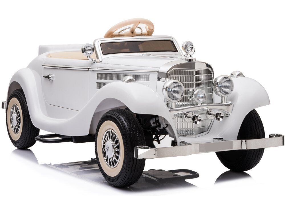 Weißes Kinderauto im Oldtimer-Stil mit offener Karosserie, verchromtem Kühlergrill, Stoßstangen und Scheinwerfern. Es besitzt helle Sitze und cremefarbene Weißwandreifen mit feinen Speichenfelgen, auf einem weißen Hintergrund mit einem dezenten Schatten.