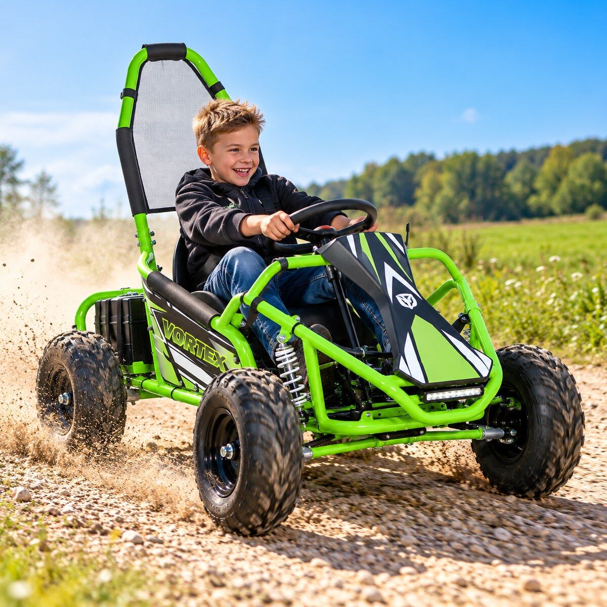 Usmívající se chlapec jede v zářivě zeleném elektrickém dětském gokartu „VORTEX“ po štěrkové cestě, za pneumatikami s hrubým vzorkem se zvedá prach. Má na sobě černou mikinu s kapucí a džíny. Pozadí: zelená pole, stromy, modrá obloha.